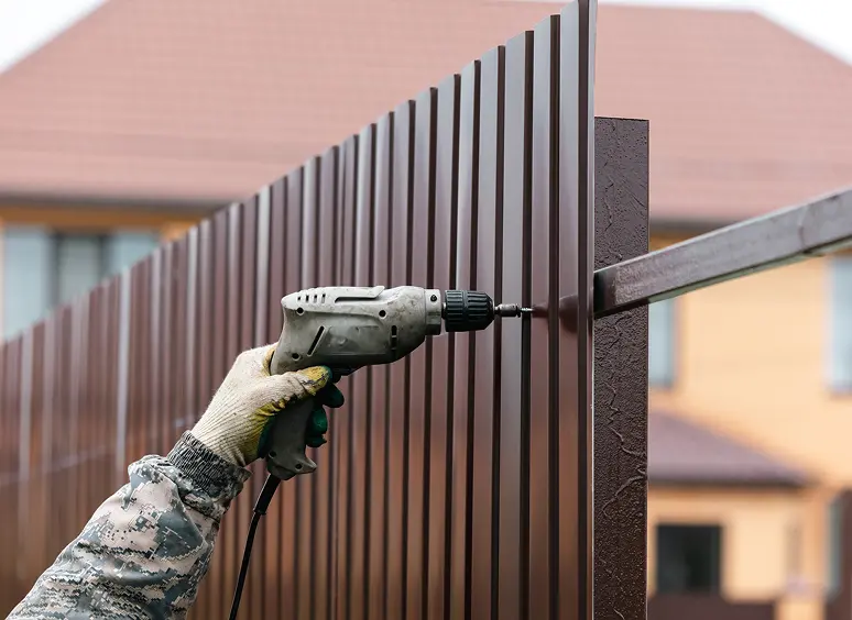 Hand using drill on outdoor fence