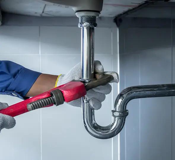 Plumber fixing sink pipe with wrench