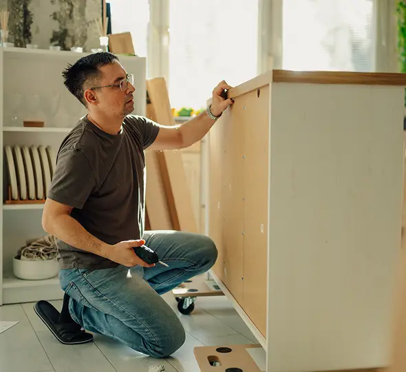 Person kneeling while building cabinet