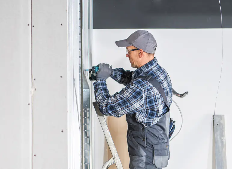 Person fixing wall with power tool