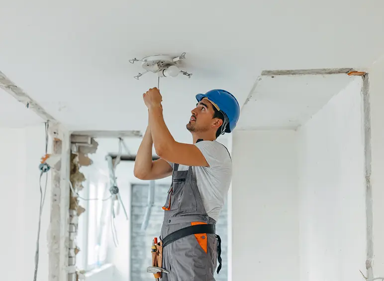 Man in hard hat adjusting light fixture